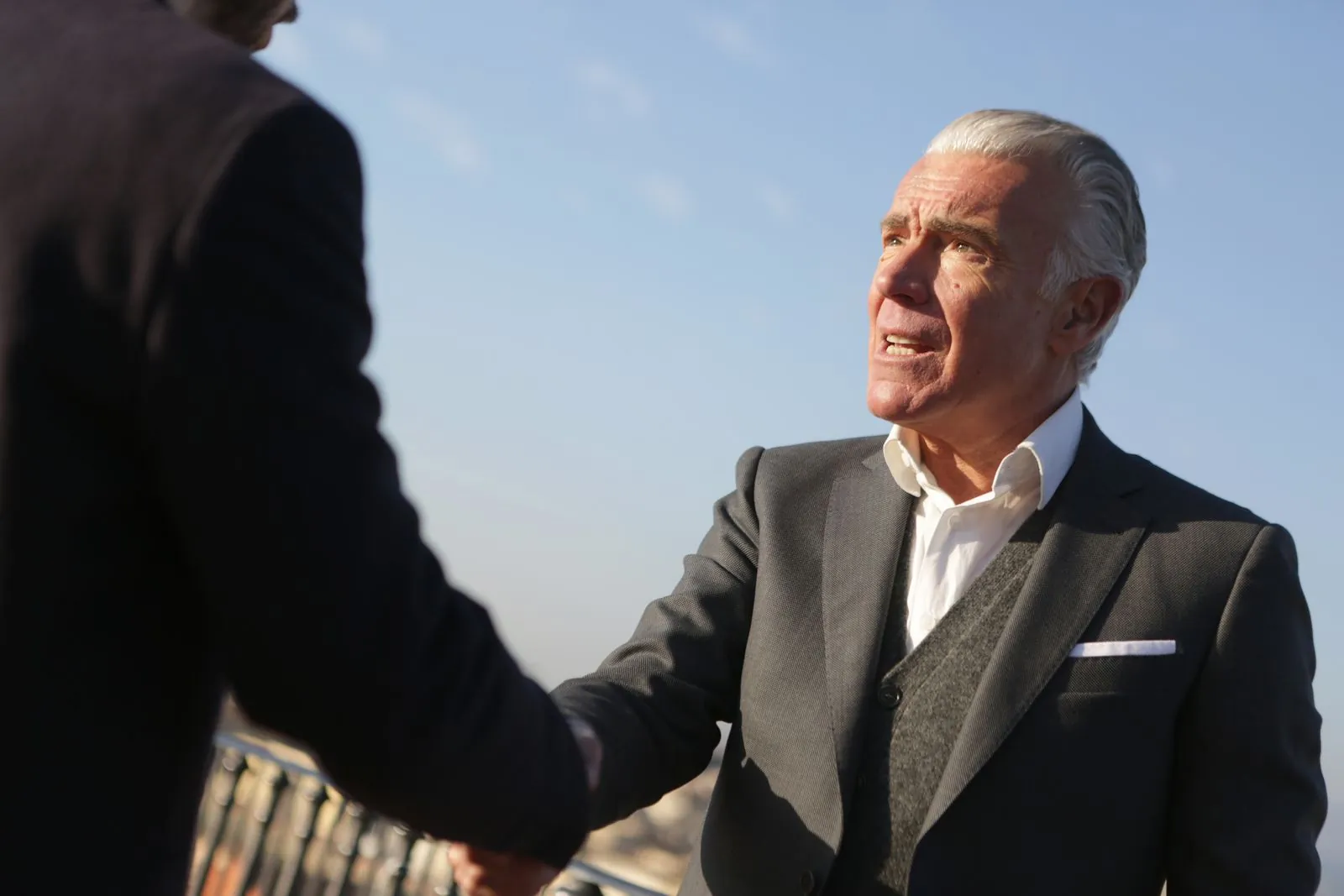 Elderly businessman shaking hands with a partner outdoors
