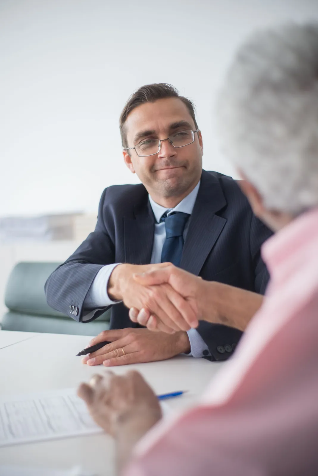 Business owner in glasses shaking hands with a service provider in an office