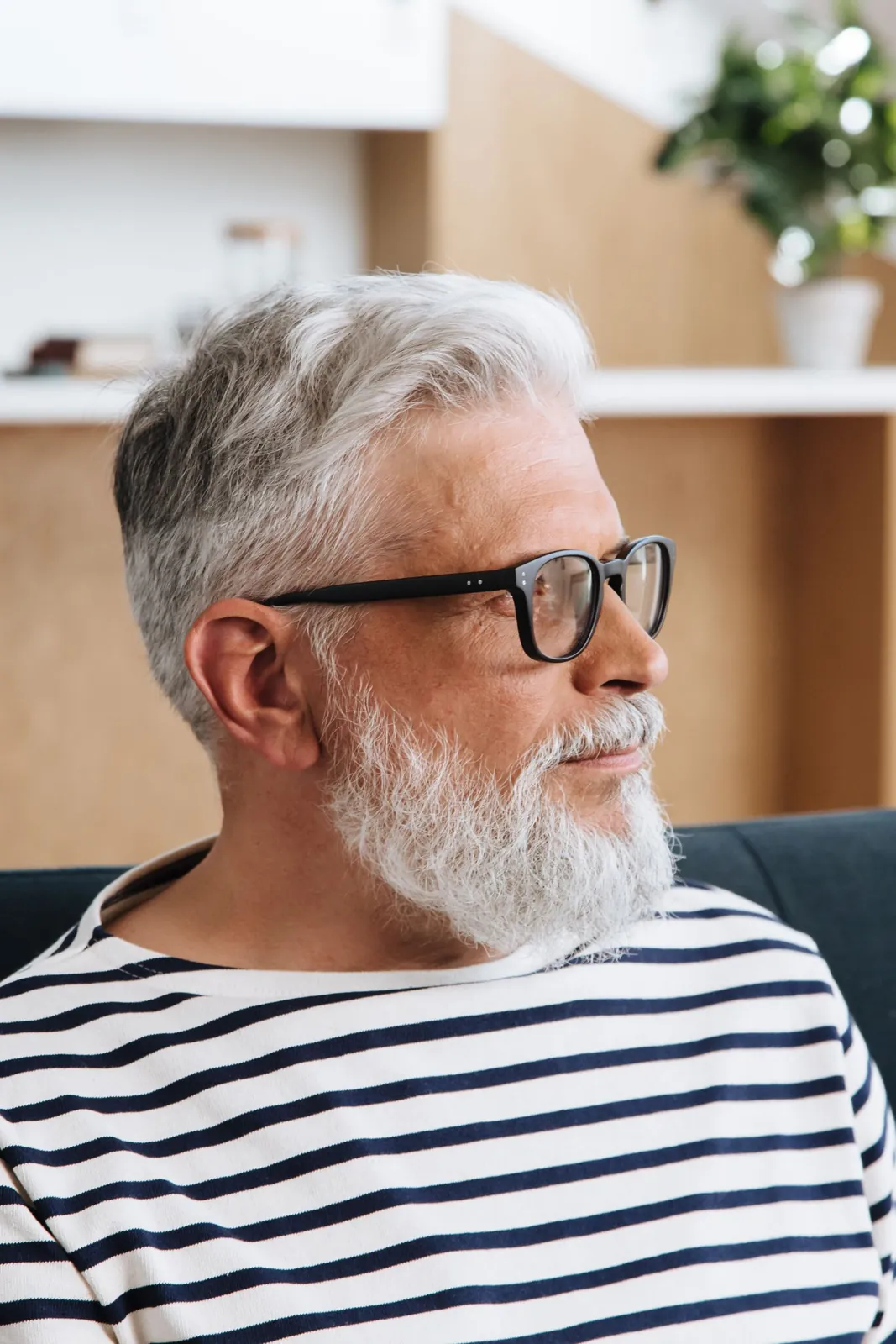 Portrait of a gray-haired man with glasses, looking thoughtful